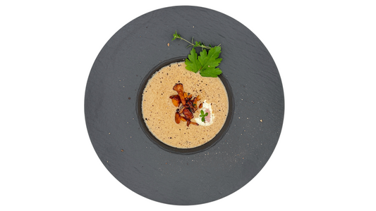 Hausgemachte Pfifferlings -Rahmsuppe mit Zitronenthymian und Sahne, serviert als Vorspeise, Garnitur Petersilie und Teelöffel Schmand. 